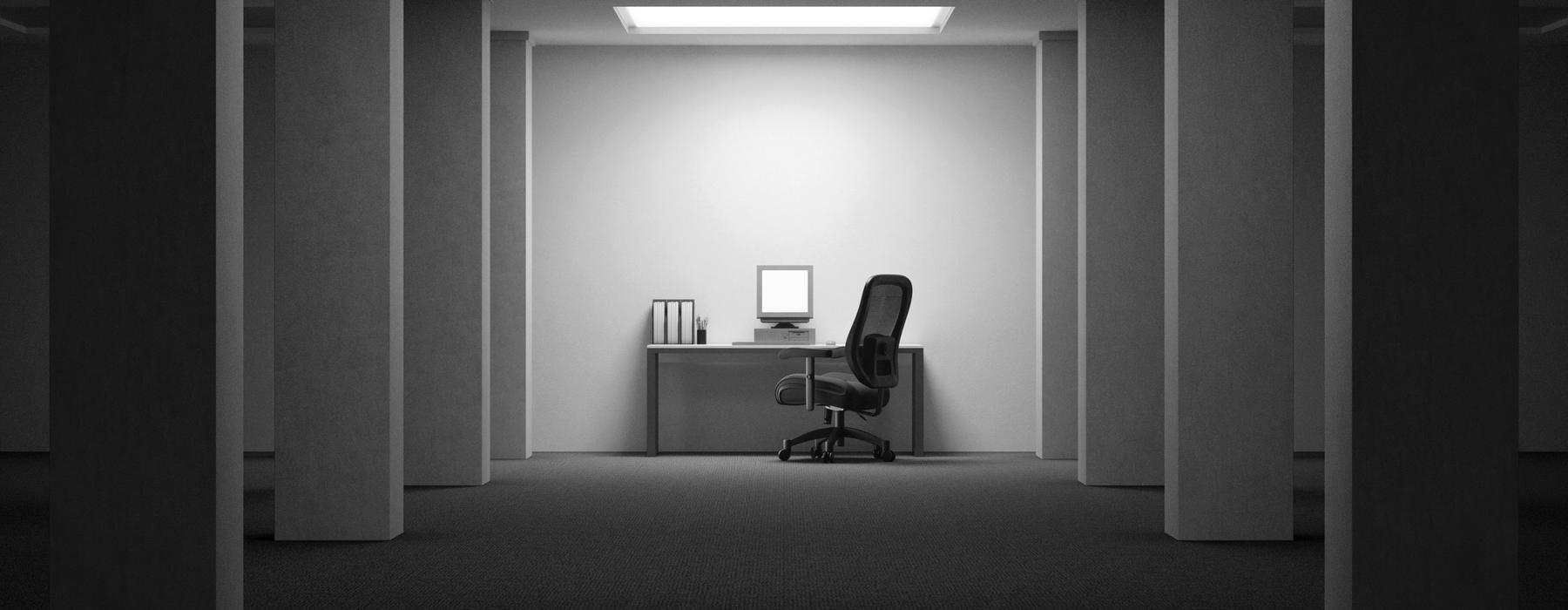 An empty office with the lights on, one desk and one chair